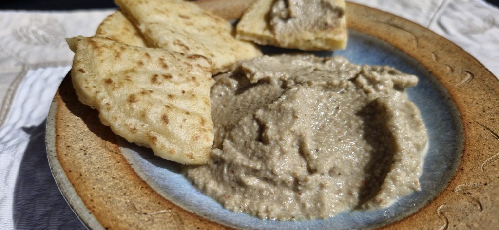 Assiette contenant le caviar d'aubergine et un blini coupé en triangles, recette légère sans ajout d'huile.