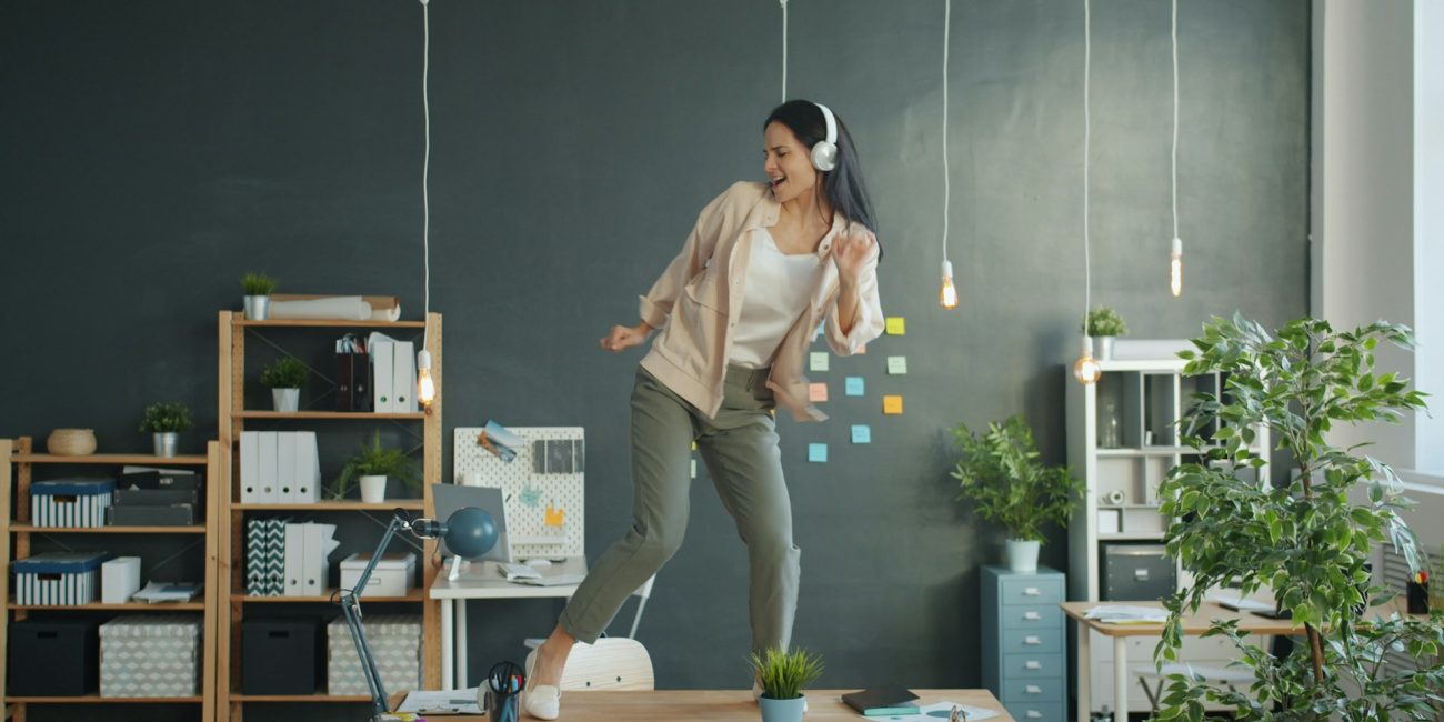Femme qui danse et chante sur son bureau.